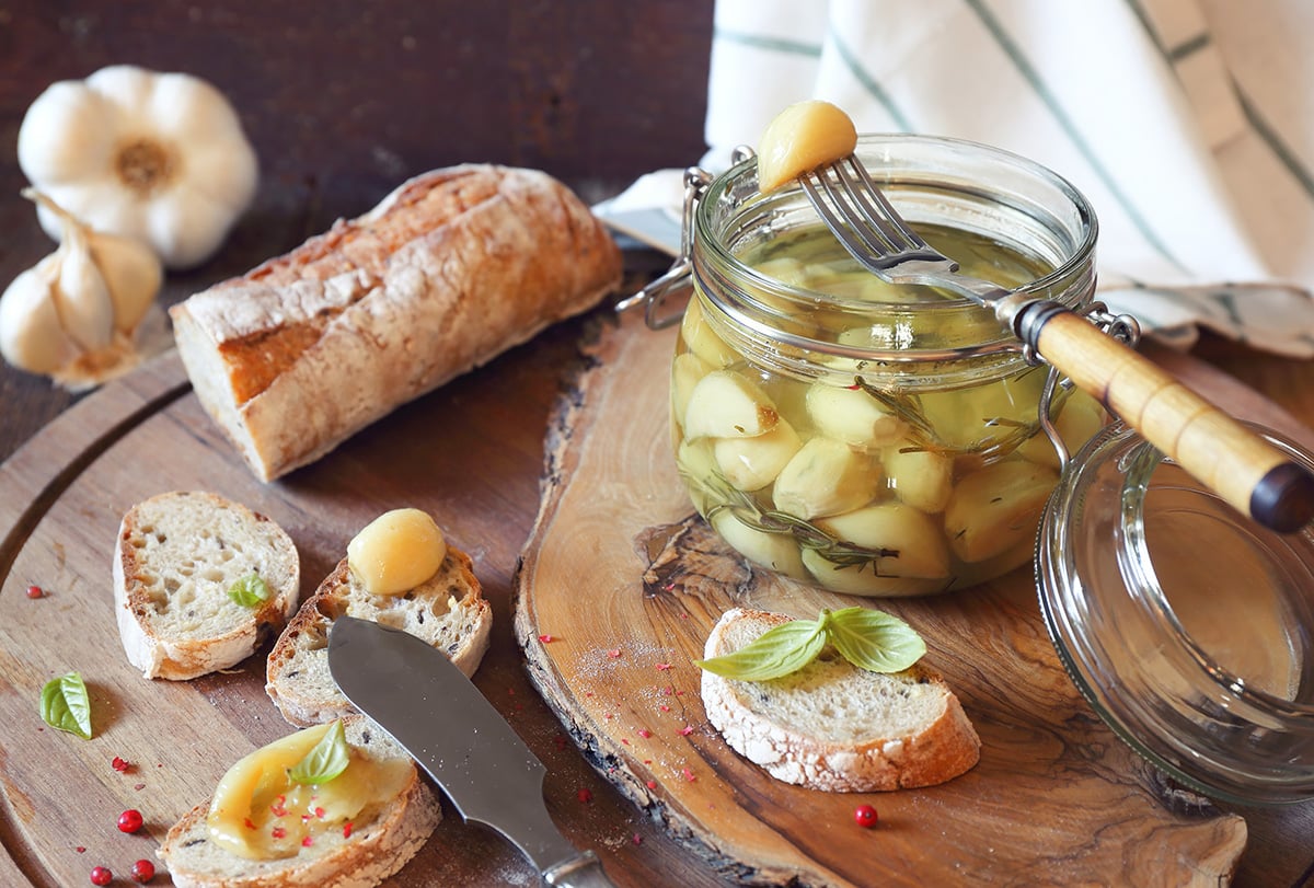wood board with confit garlic in a jar with bread