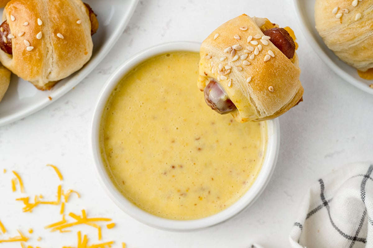 Pig in a blanket dipping into honey mustard dipping sauce 