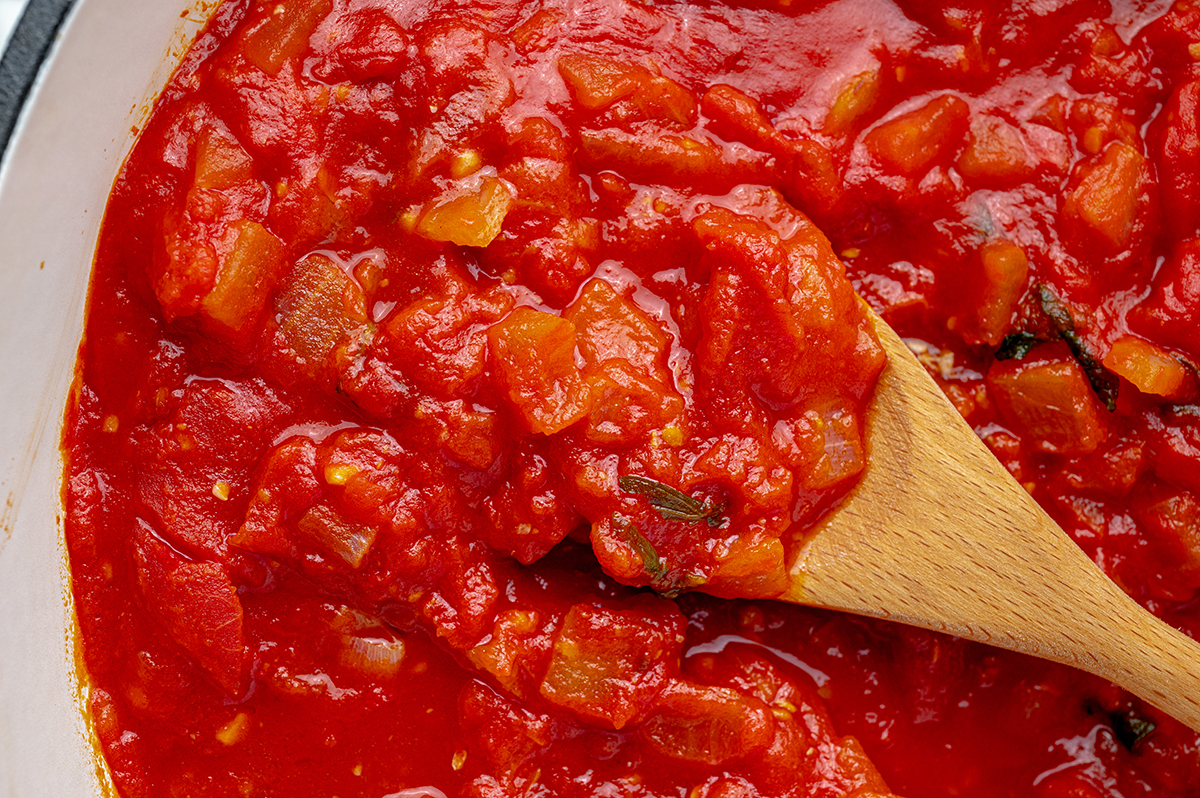 close up of marinara in a pan with a wooden spoon