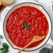 overhead shot of marinara in a pan with a wooden spoon