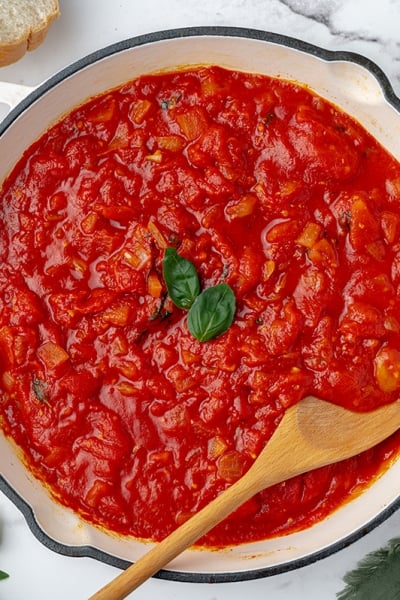 overhead shot of marinara in a pan with a wooden spoon