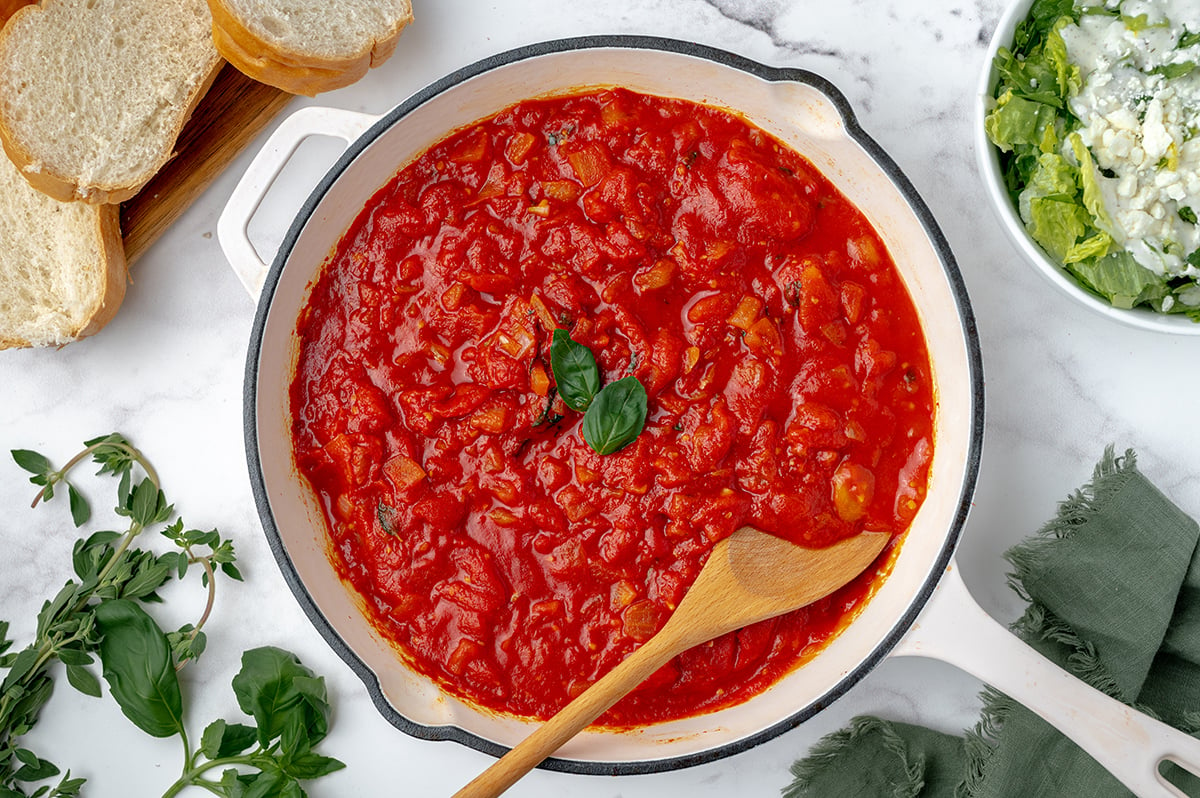 overhead shot of marinara in a pan with a wooden spoon