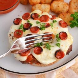 fork cutting into an open face pizza burger