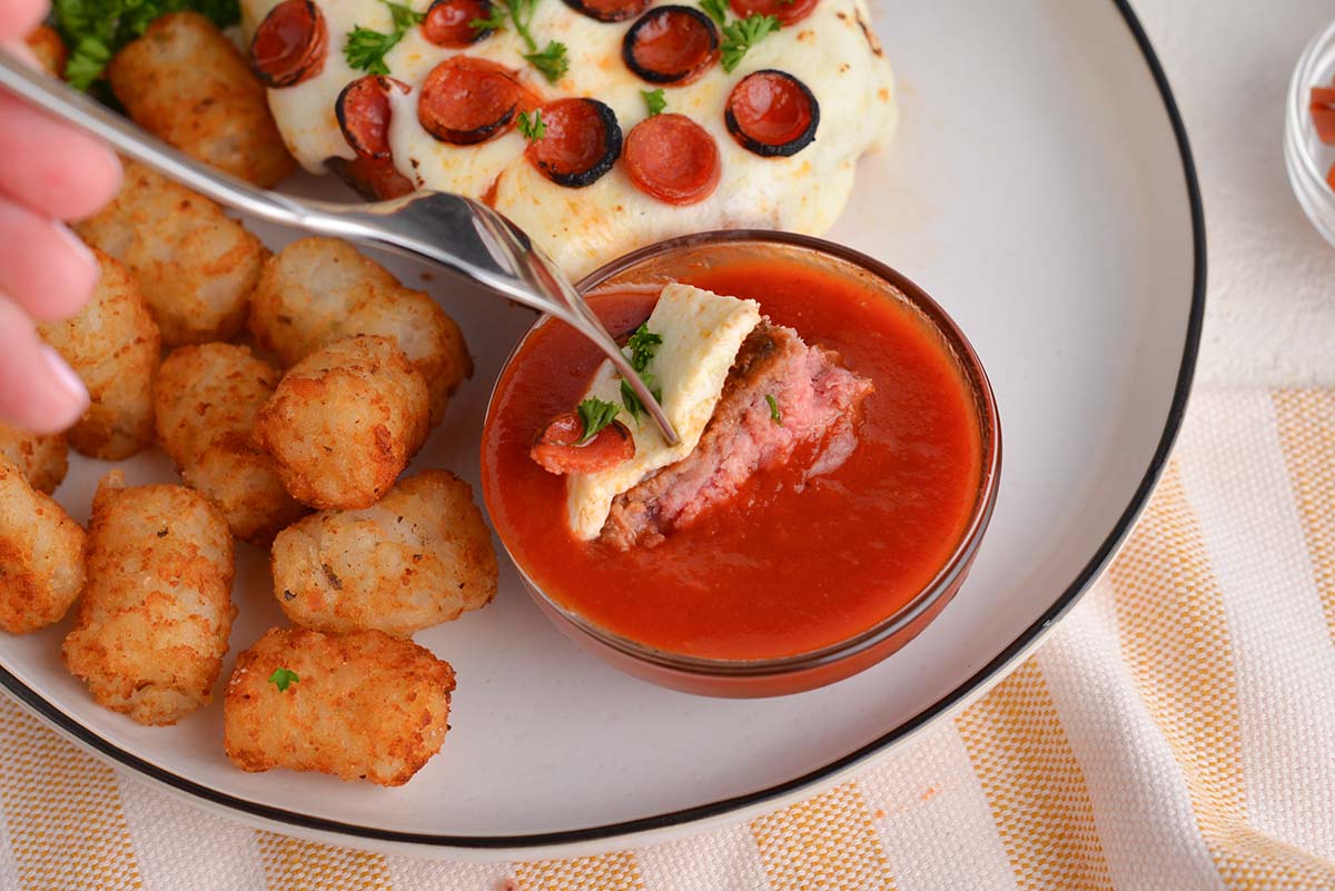 bite of pizza burger dipping into marinara sauce 