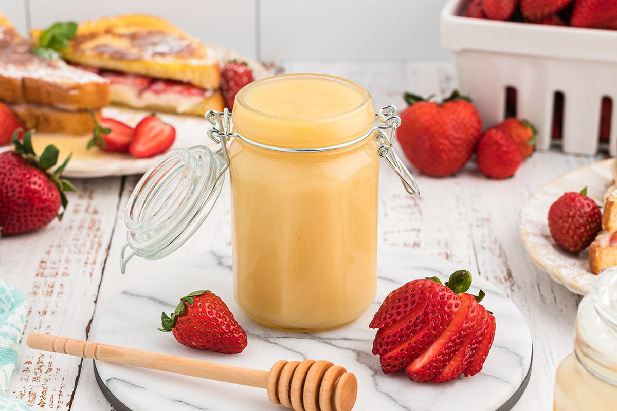 glass jar of homemade syrup with fresh strawberries 