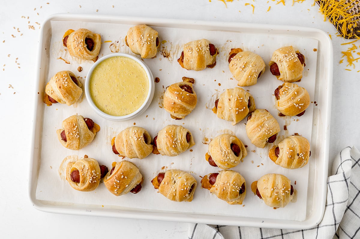 pigs in a blanket with sesame seeds on a baking sheet 