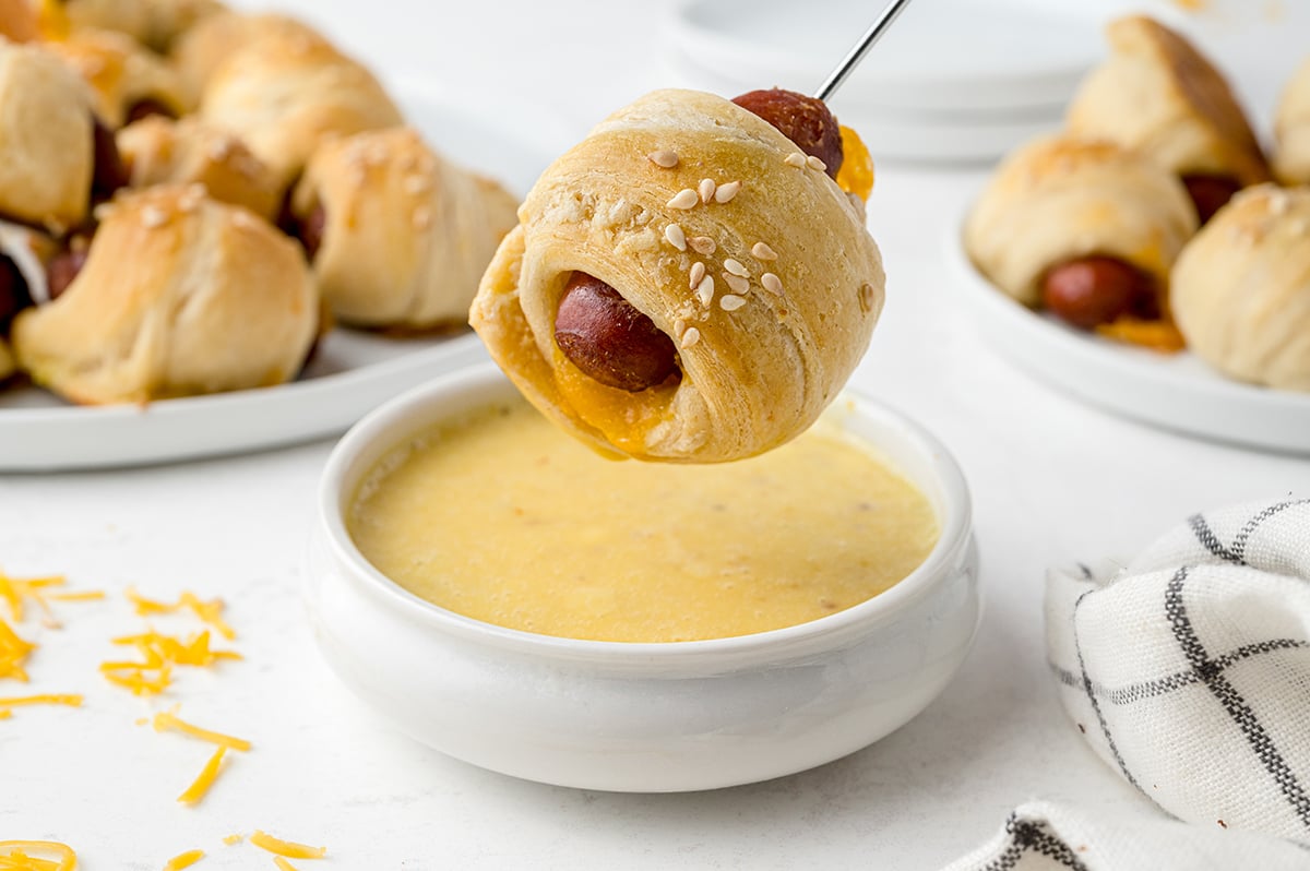 dipping a pig in a blanket in honey mustard sauce 