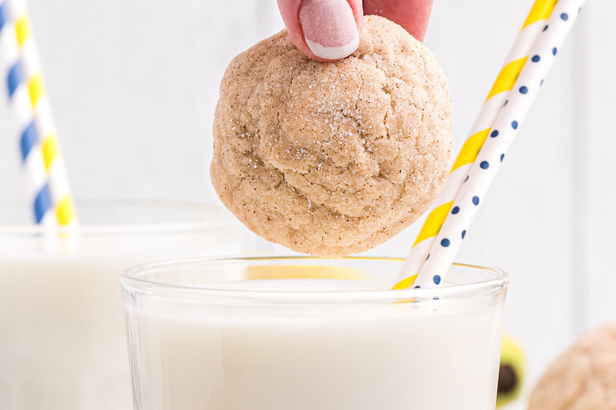 hand dipping a cookie into a glass of milk 