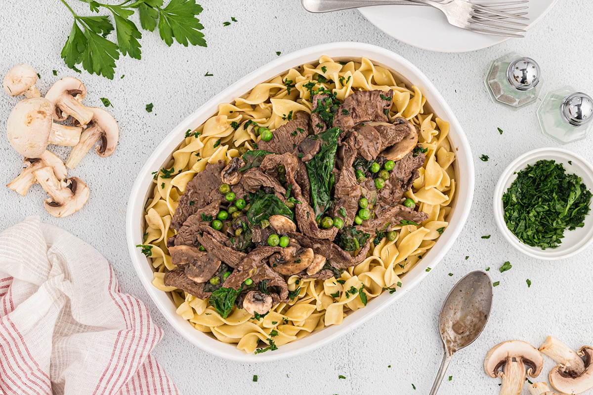 overhead of beef with spinach and peas in a serving dish 