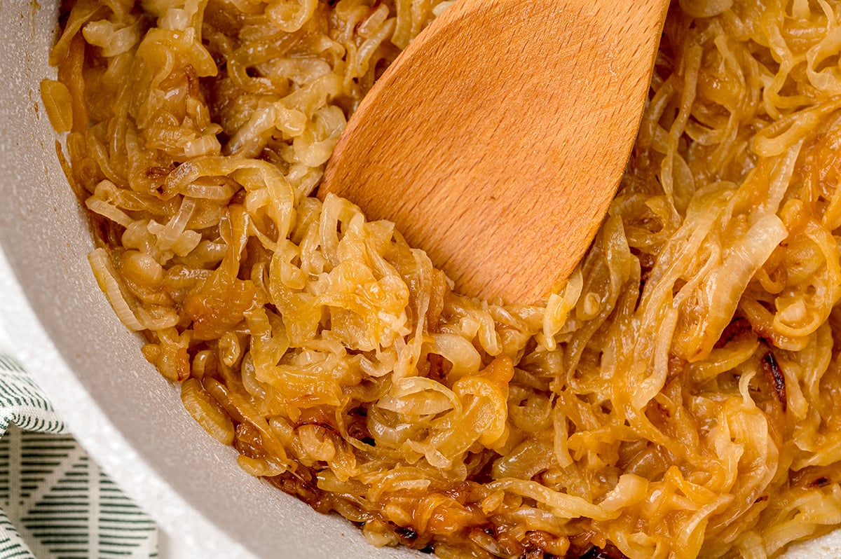 caramelized onions in a pan with a wooden spoon