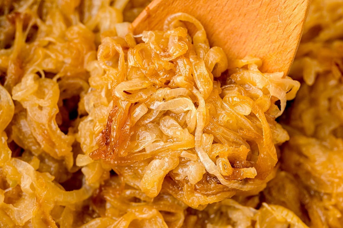 close up of caramelized onions on a wooden spoon