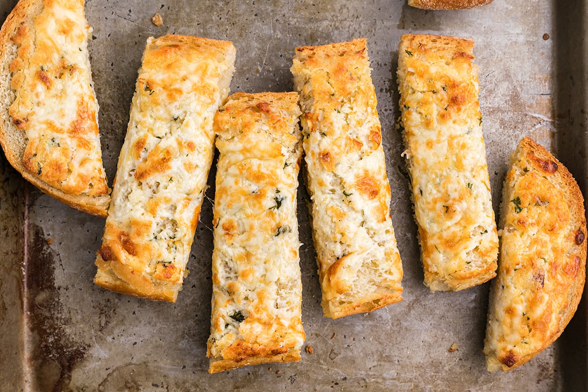 cut up bread sticks with garlic spread on a baking sheet 