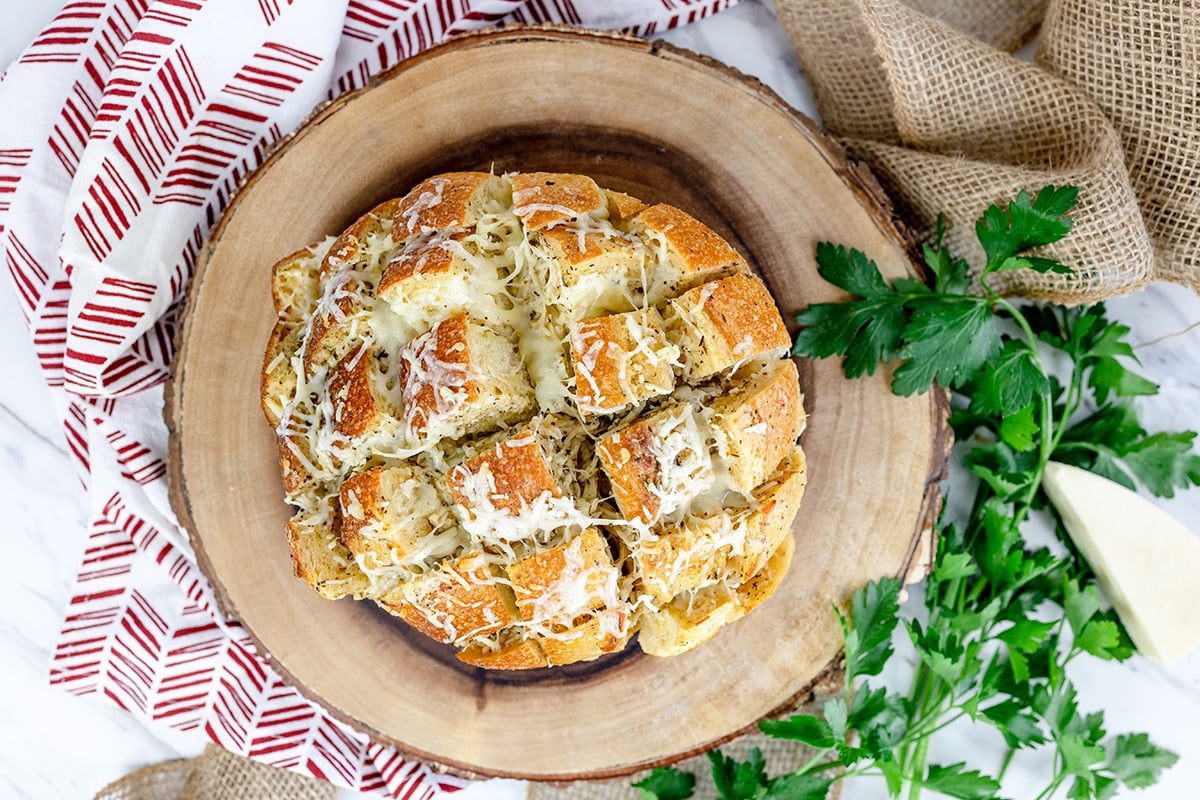 pull apart bread on a piece of wood with parsley 