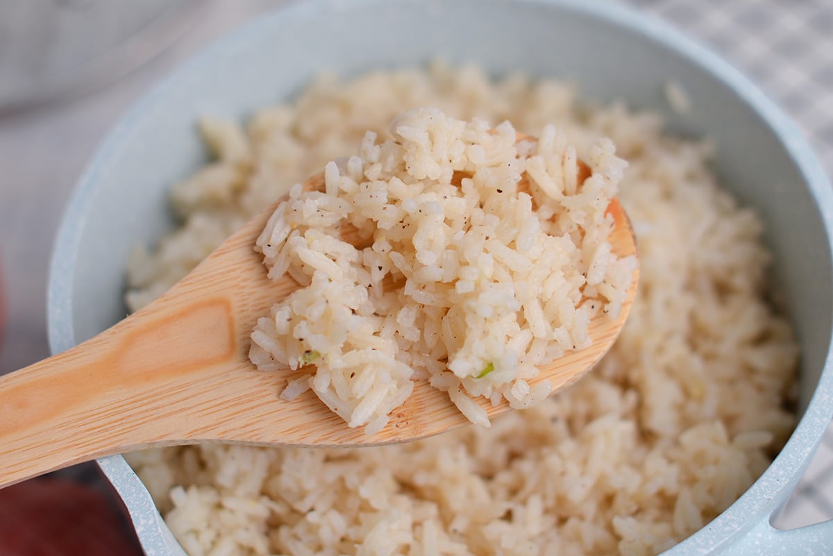 wooden spoon holding cooked ginger rice 