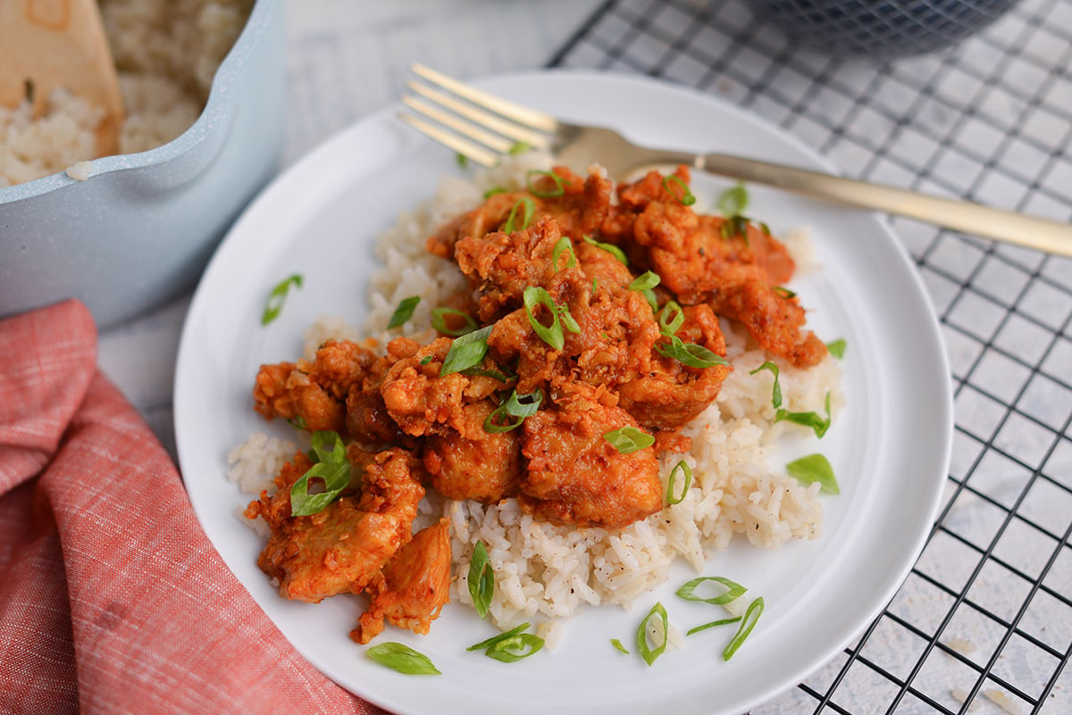 orange chicken over asian rice recipe on a white plate 