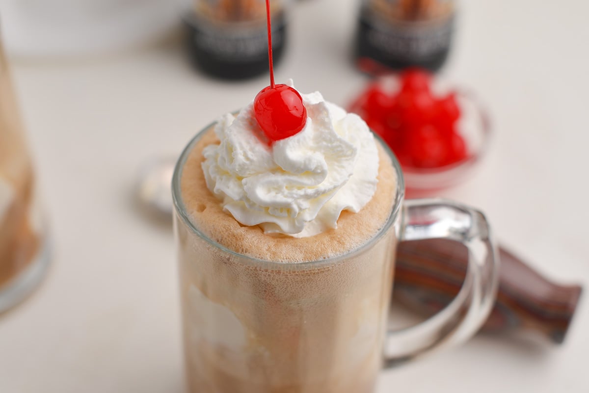 close up of whipped cream and a cherry on a brown cow float