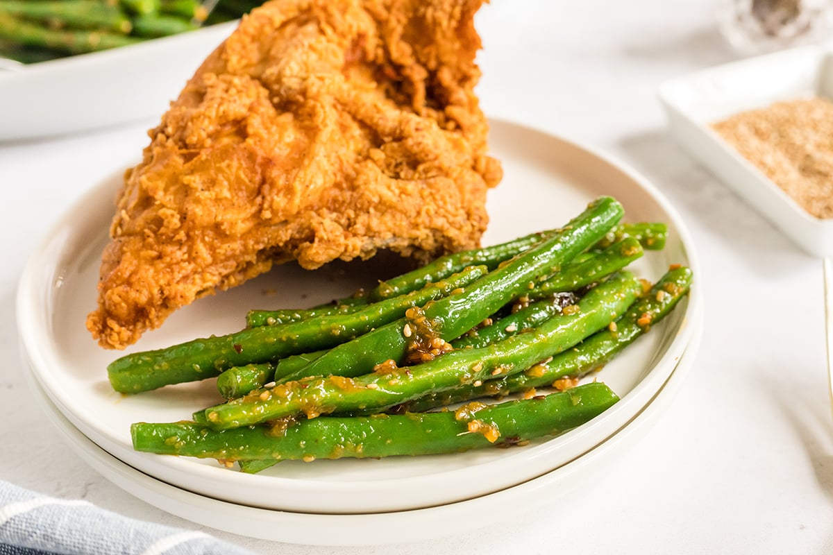 close up shot of pf changs green beans on a plate with chicken