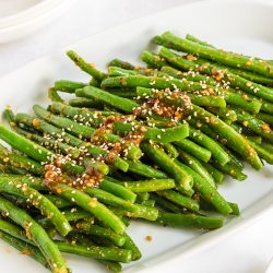 close up of spicy green beans on a white platter