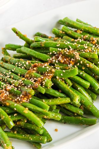 close up of spicy green beans on a white platter