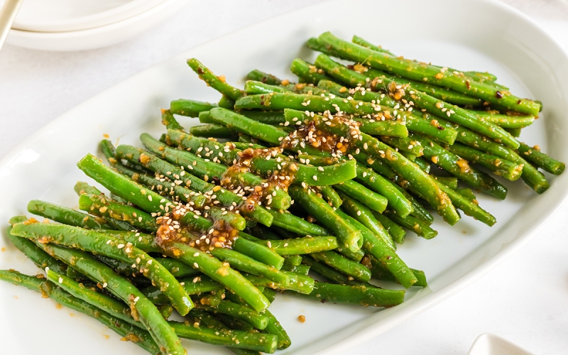 close up of spicy green beans on a white platter