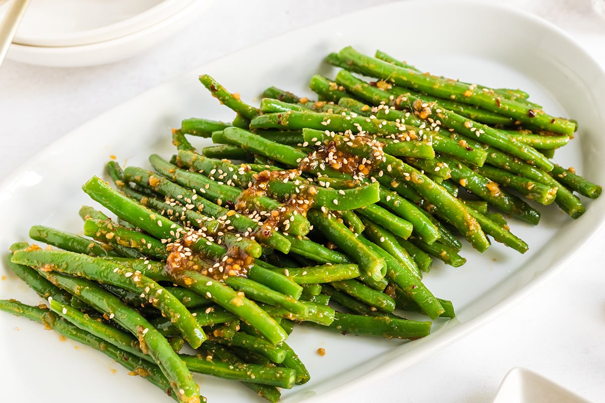 close up of spicy green beans on a white platter