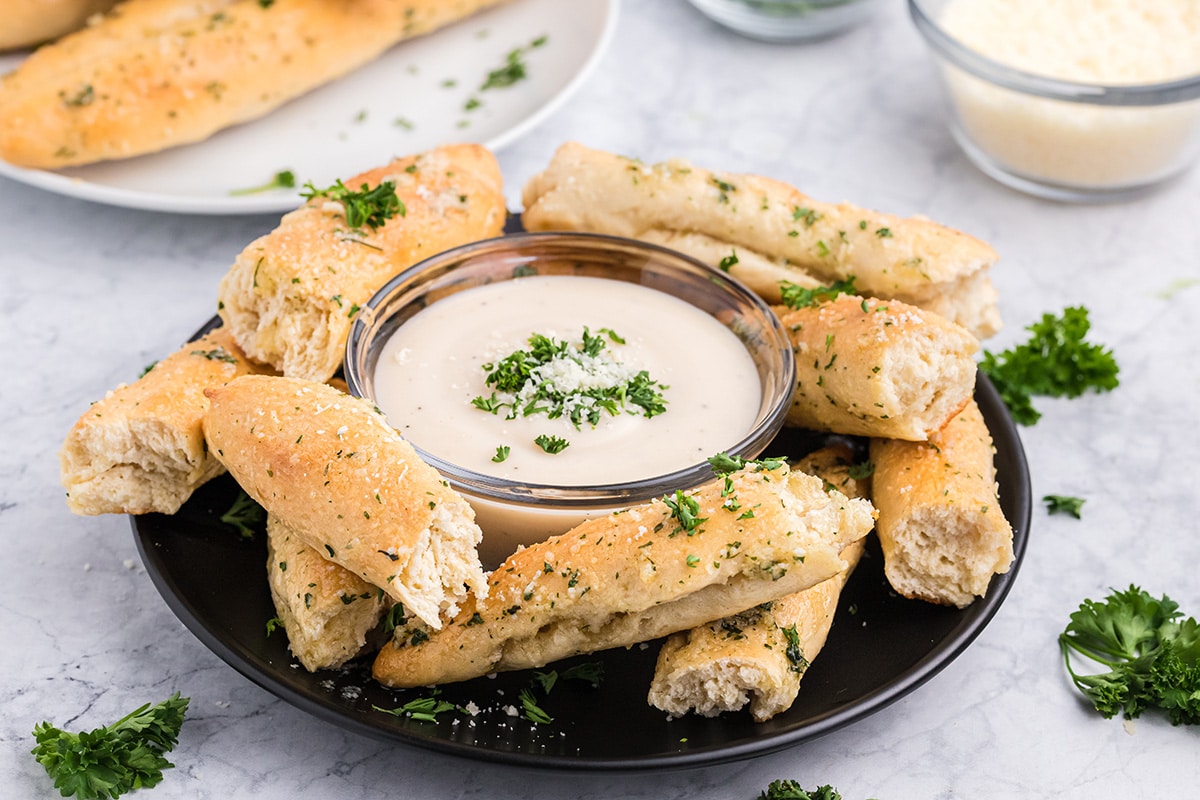 serving platter of homemade breadsticks with dipping sauce