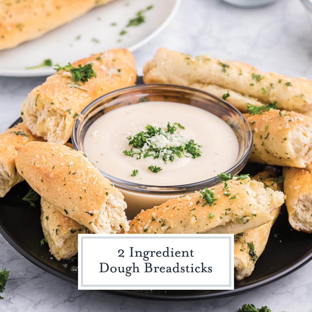 homemade breadsticks with no yeast on a serving platter with alfredo dipping sauce
