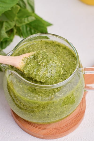 spoon in jar of basil pesto sauce