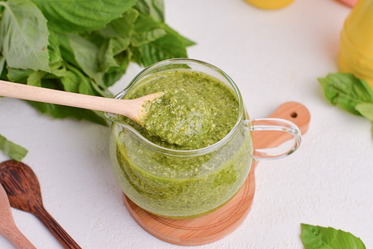 spoon in jar of basil pesto sauce