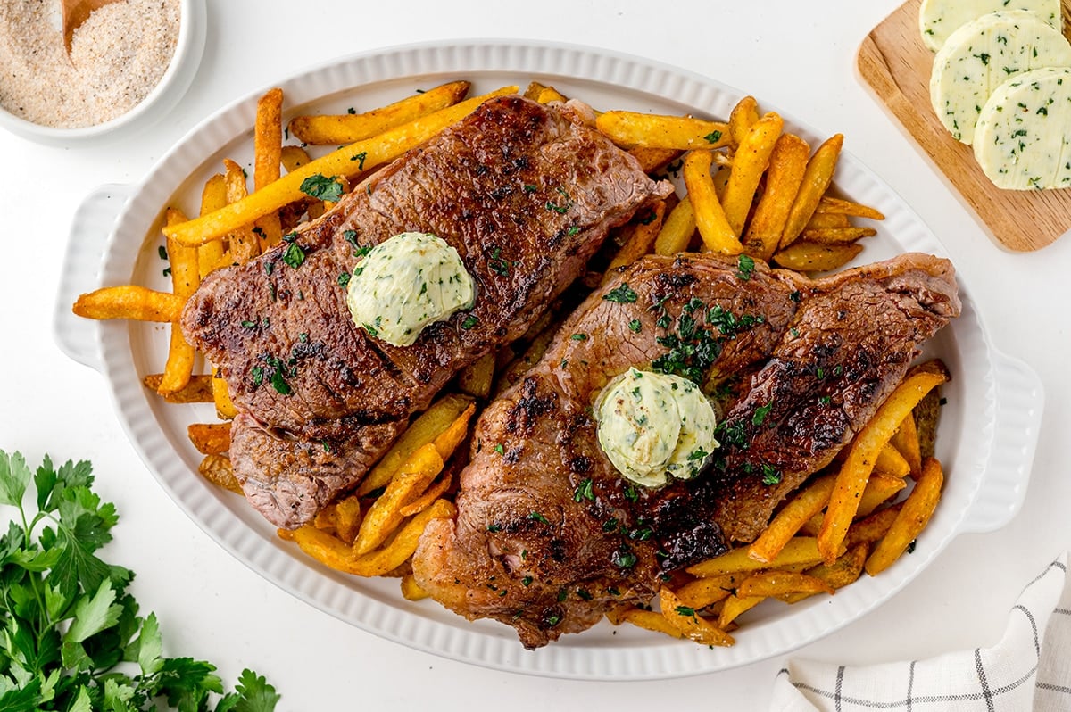 two steaks on a tray with fries