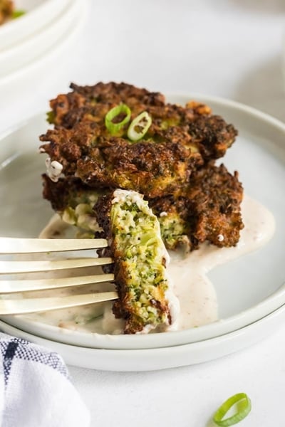 bite of broccoli fritters dipping into sauce