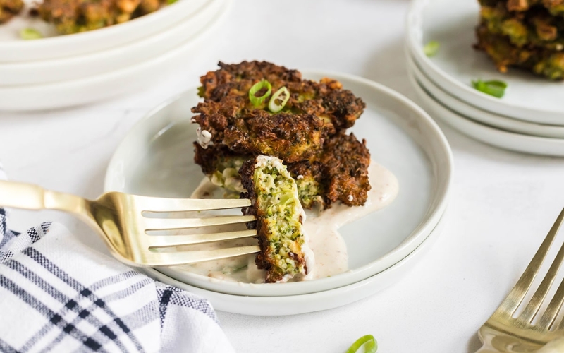 bite of broccoli fritters dipping into sauce