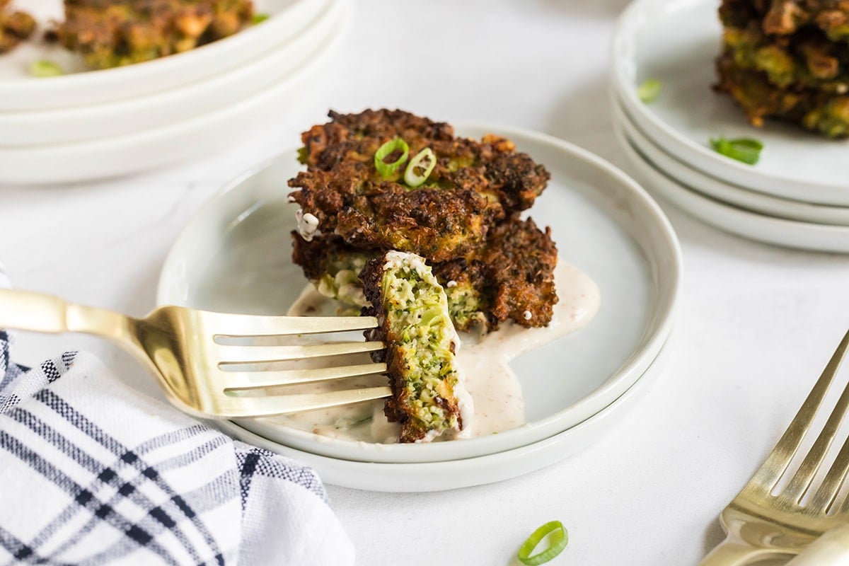 bite of broccoli fritters dipping into sauce