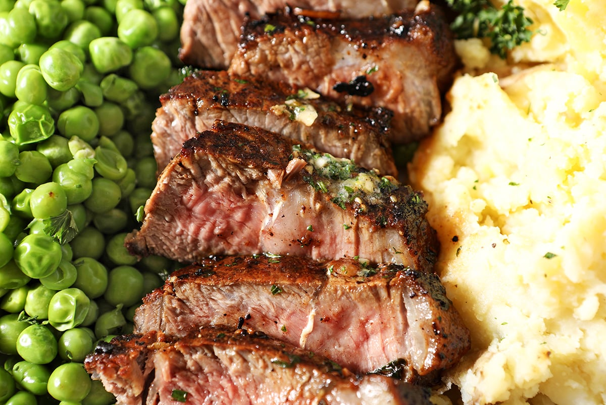 garlic butter sirloin steak sliced with potatoes and peas
