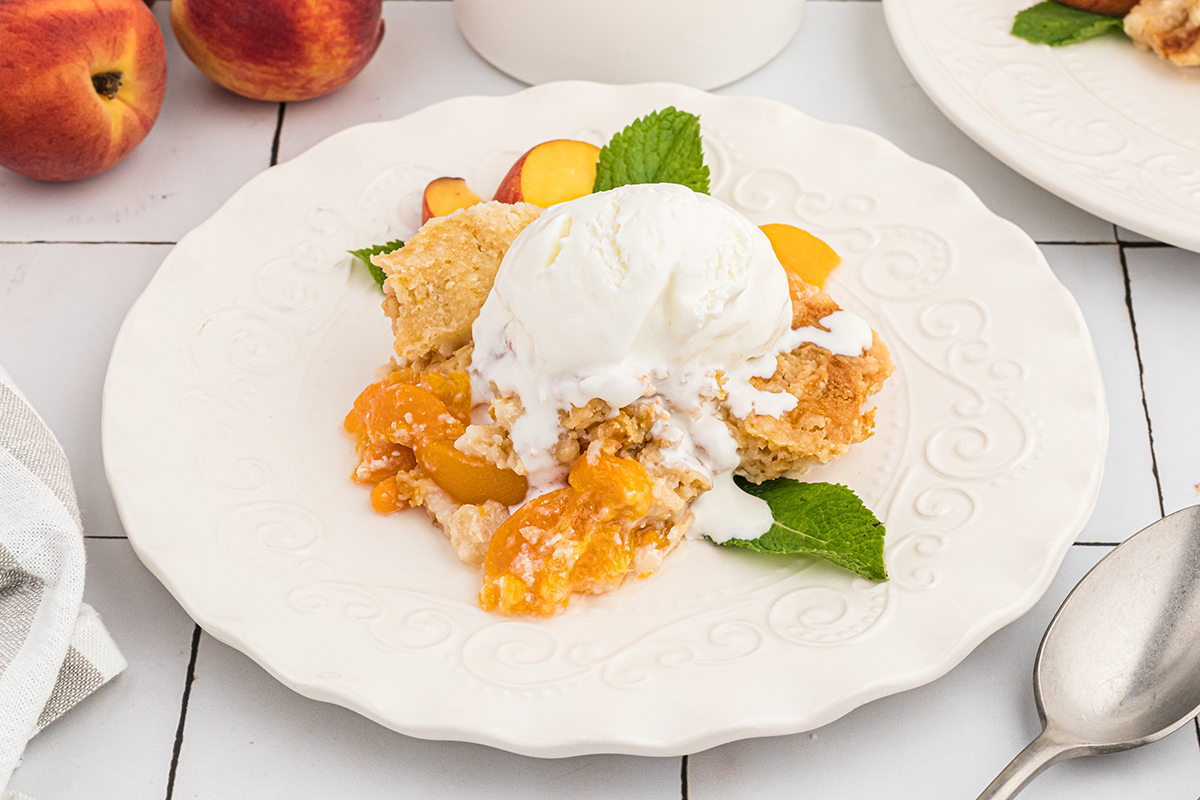 angled shot of peach dump cake topped with ice cream