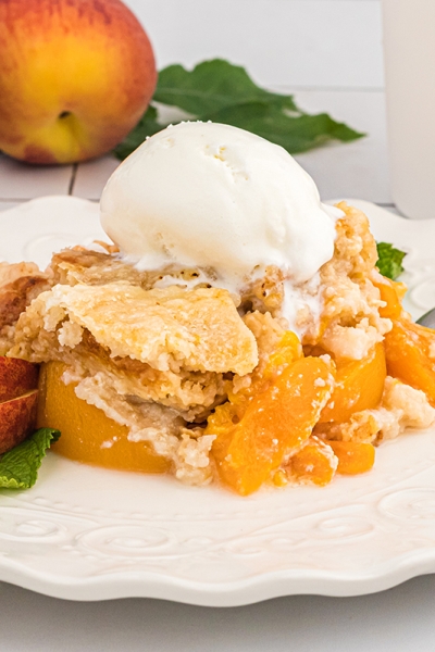 straight on shot of peach dump cake topped with ice cream