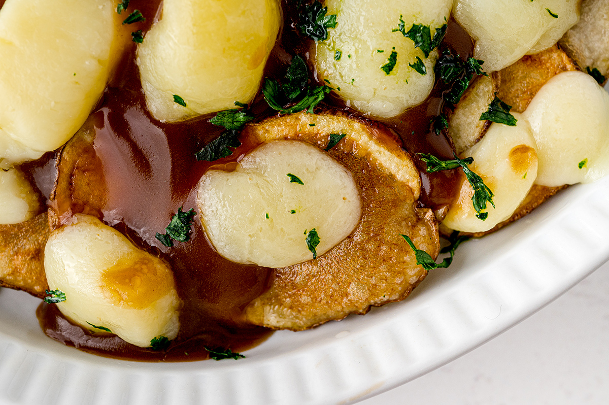 close up of melted cheese curds on fried potatoes 