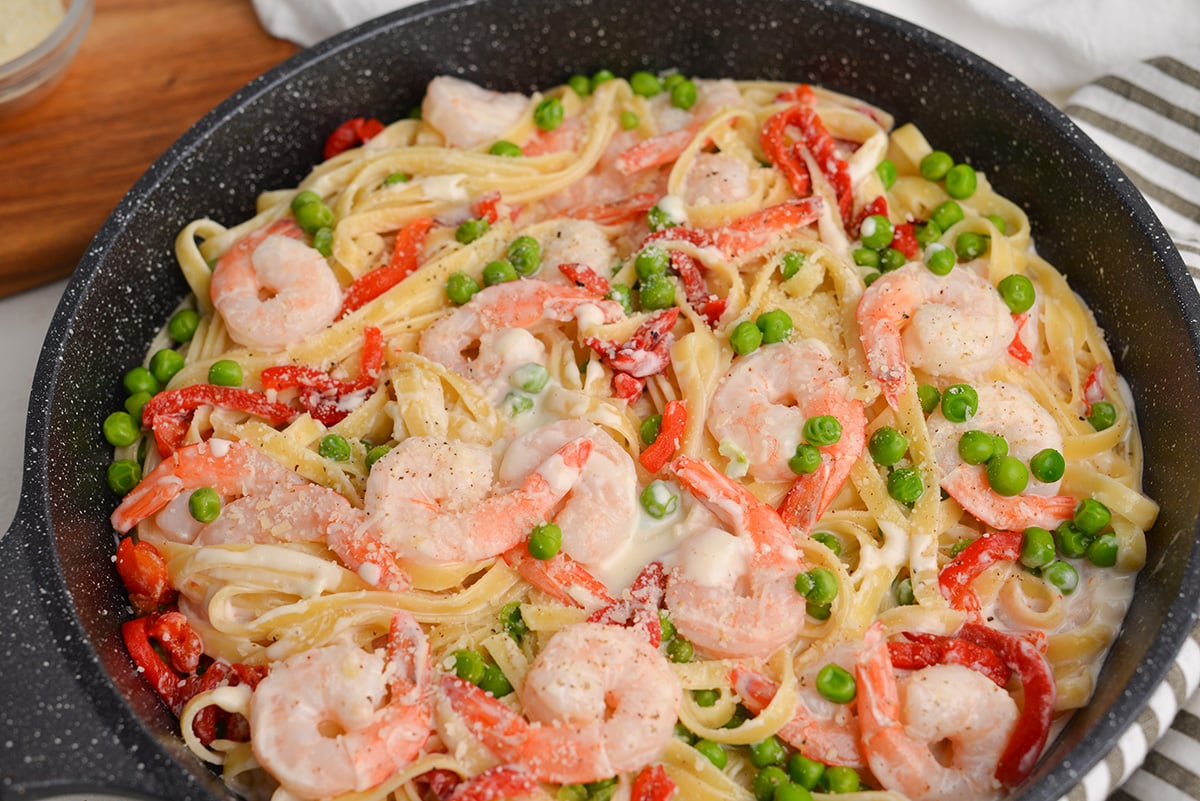 close up angle of fettuccine alfredo with shrimp, peas and red pepper