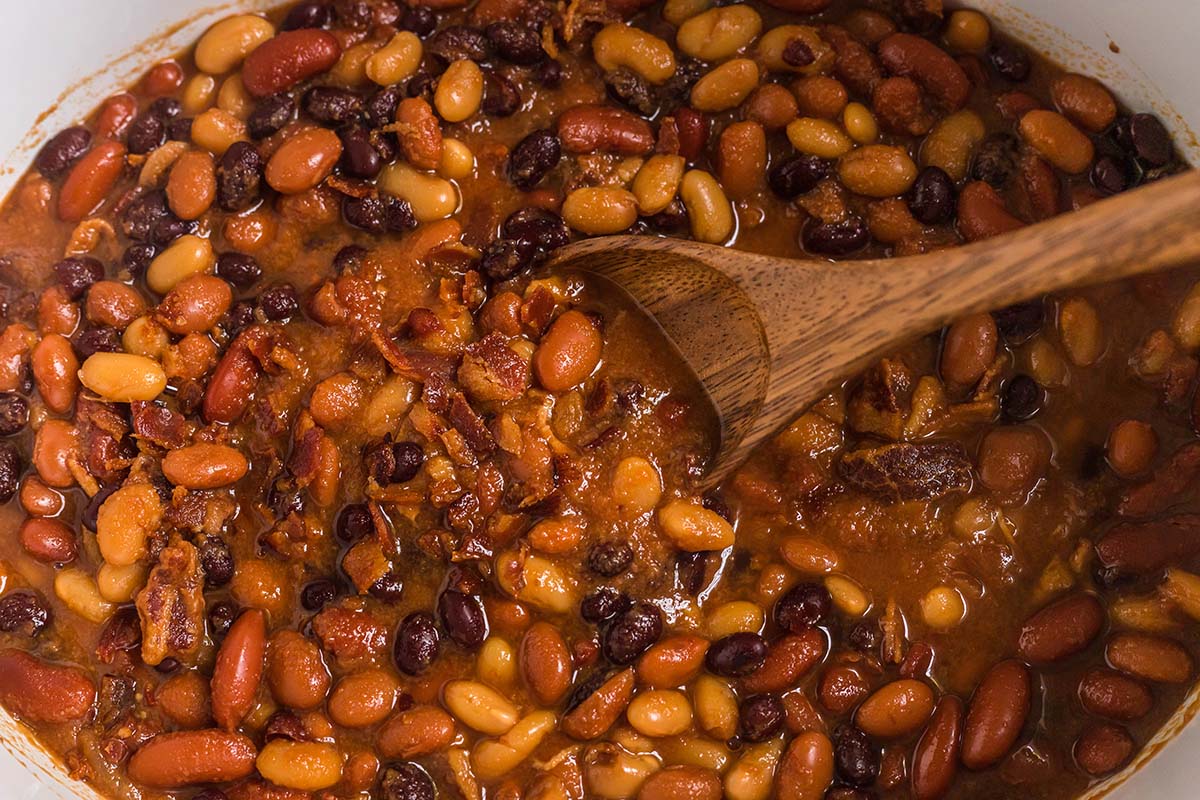 baked beans in a crock pot with wooden spoon