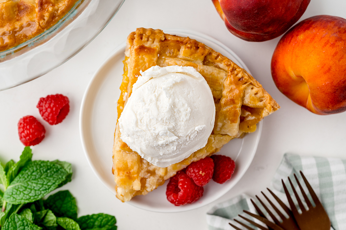 overhead shot of slice of peach pie topped with ice cream