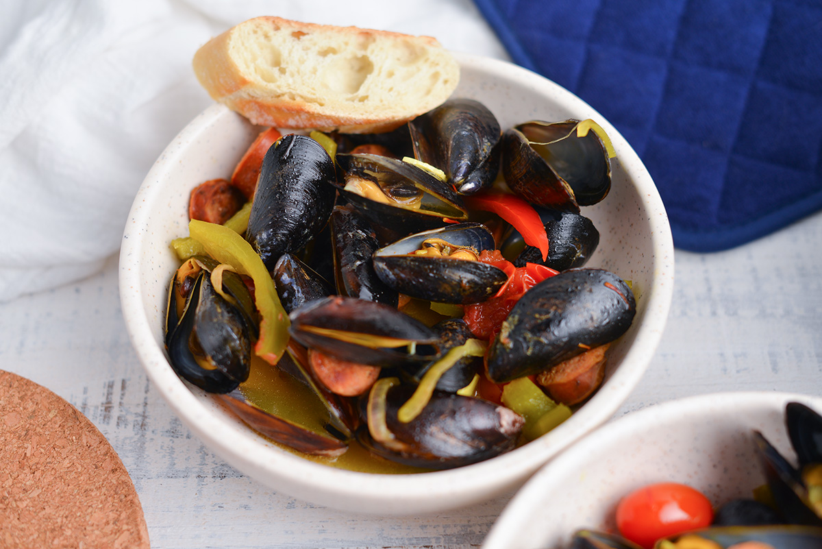 steamed mussels in a saffron broth in a bowl bowl with a slice of bread 