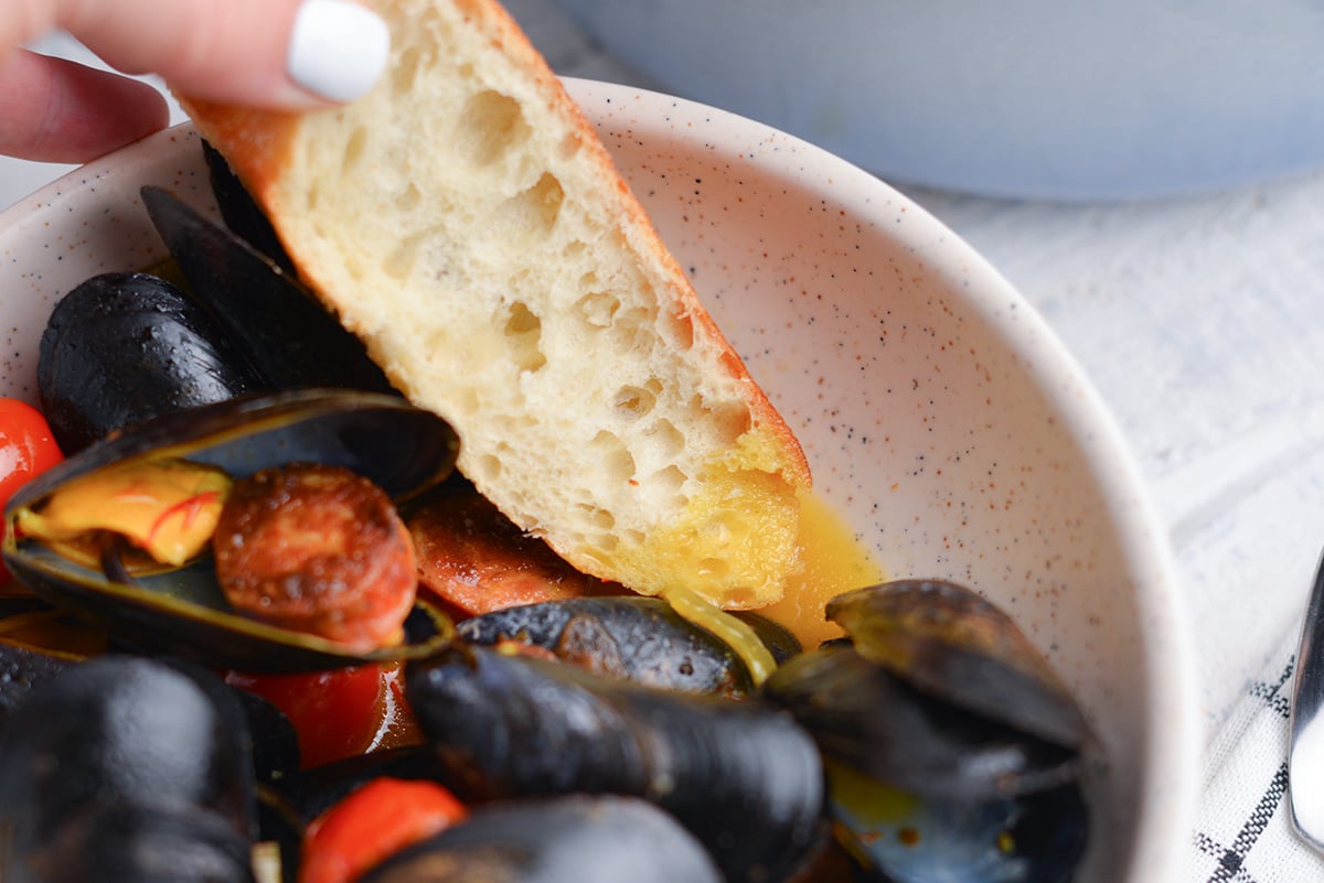 piece of bread dipping into saffron butter broth 