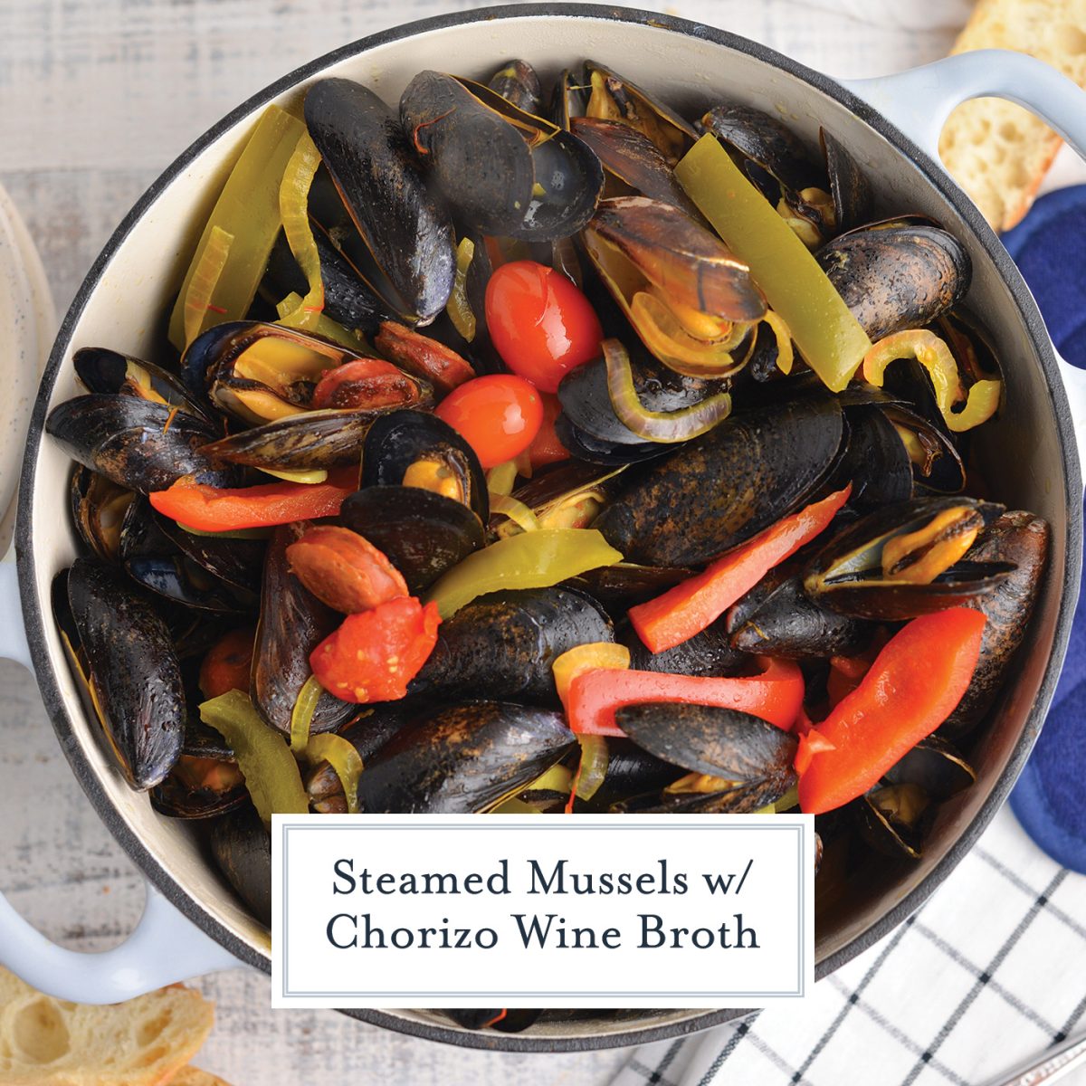 overhead of steamed mussels in a dutch oven with tomatoes and bell pepper