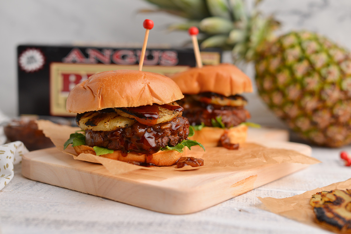 two burgers sitting on a wood cutting board