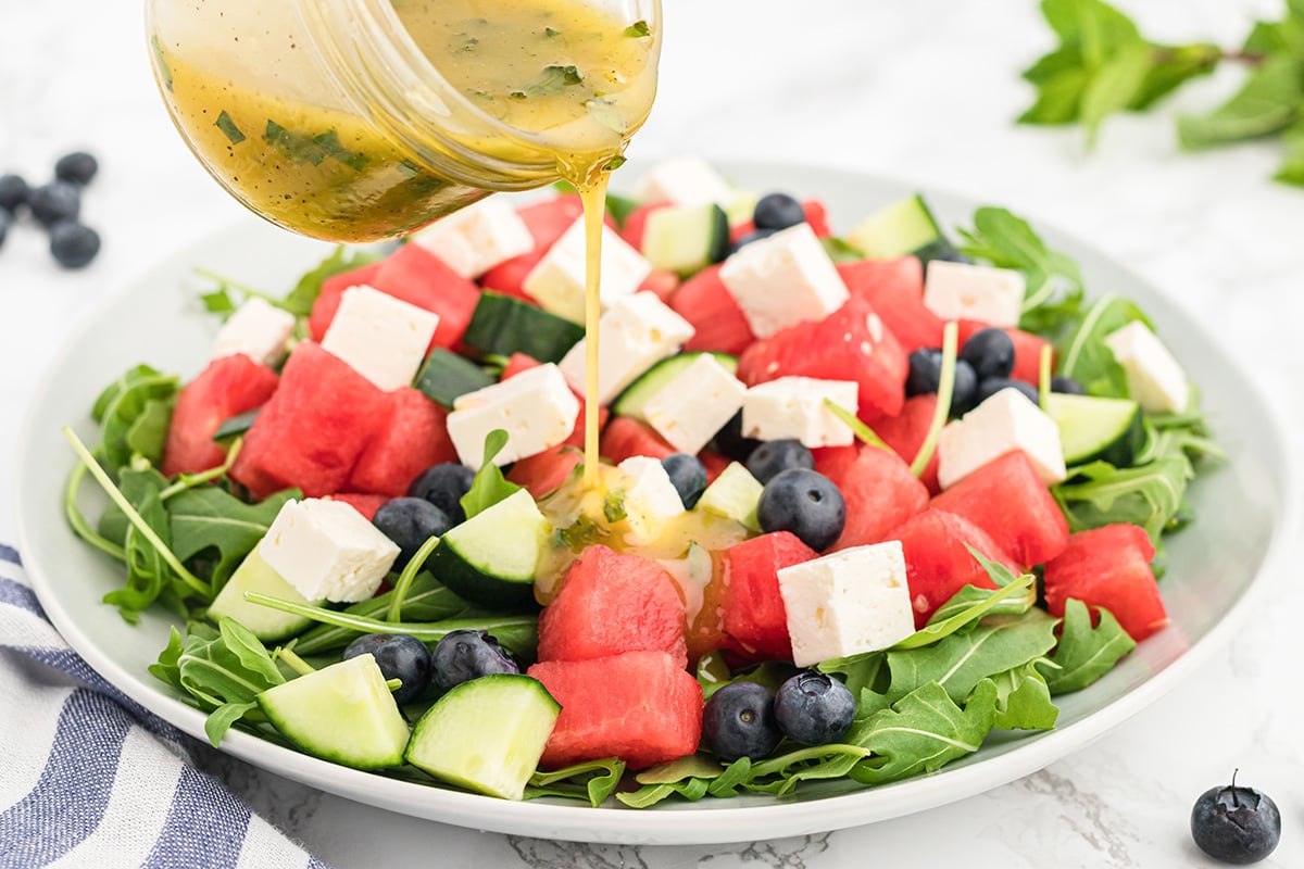 dressing poured onto watermelon feta salad