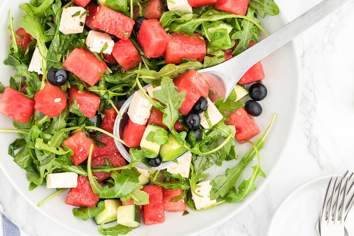 overhead shot of bowl of watermelon feta salad with serving spoon