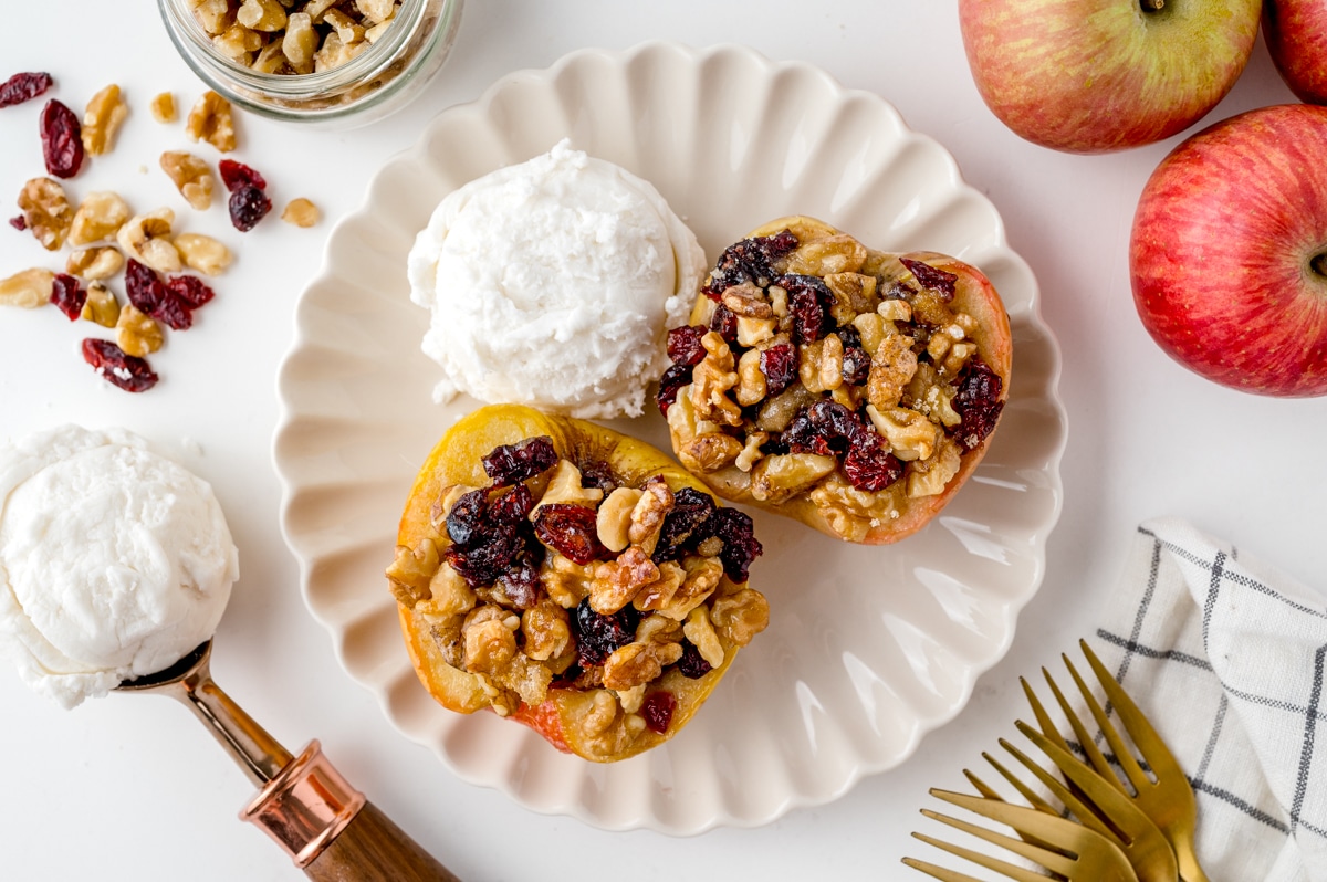 two baked apples on a plate with ice cream