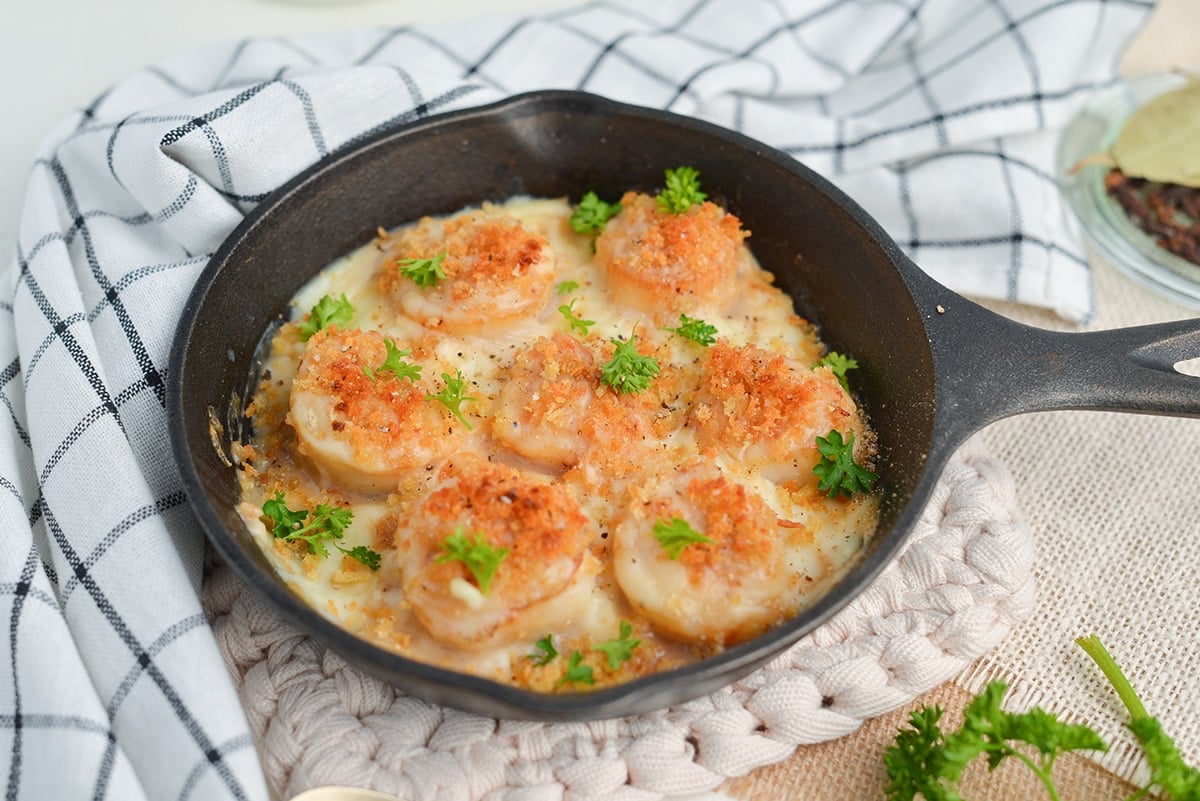 Angle view of scallops in a mini cast iron skillet with creamy sauce