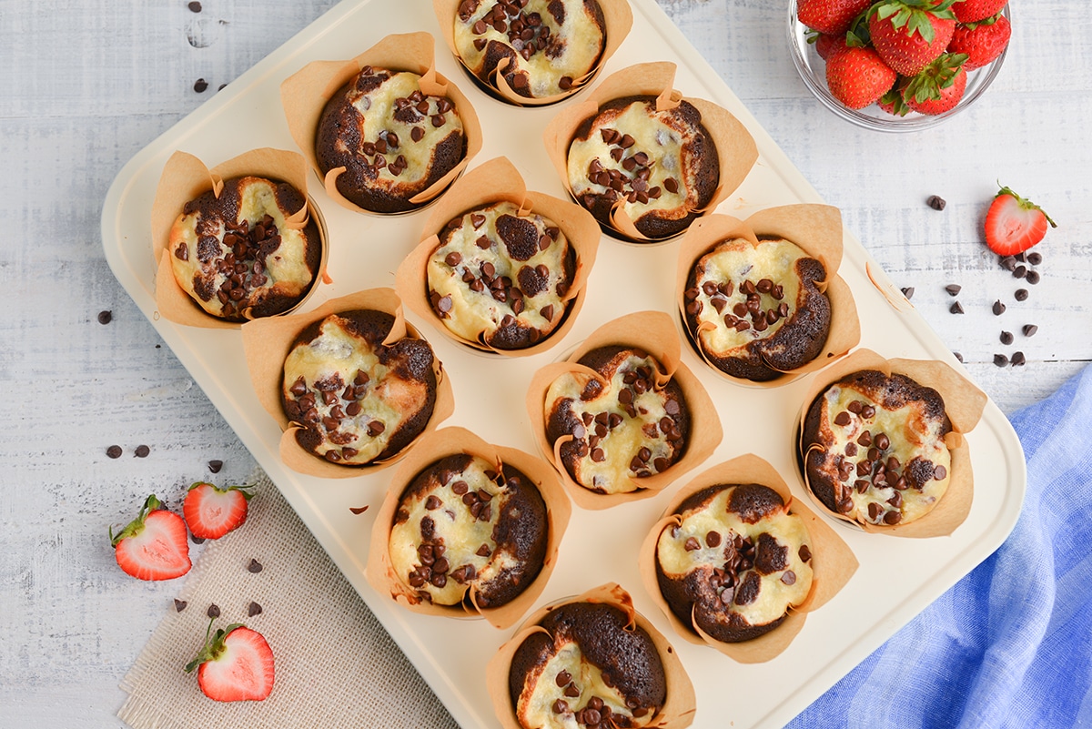 overhead black bottom cupcakes in a muffin tin with strawberries