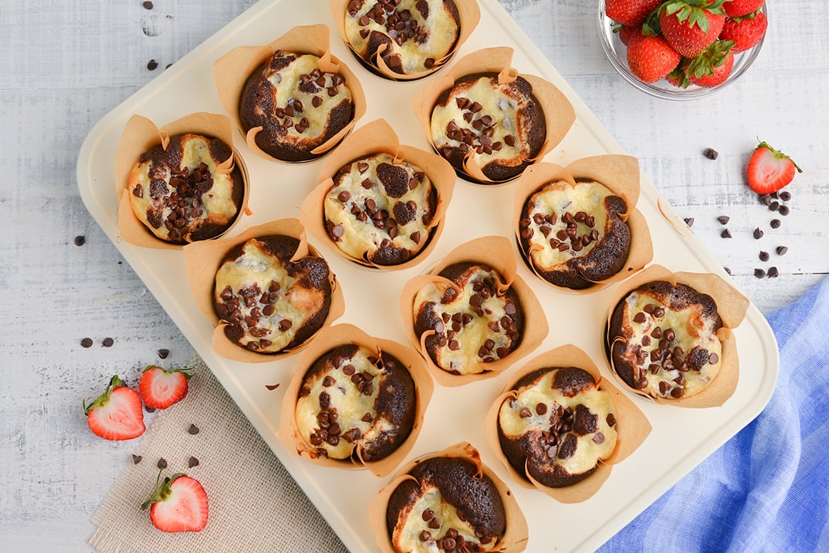 overhead black bottom cupcakes in a muffin tin with strawberries